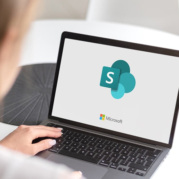 Person using laptop with SharePoint logo on the screen.