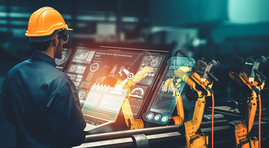Man with hard hat looking down at a screen within a factory environment.