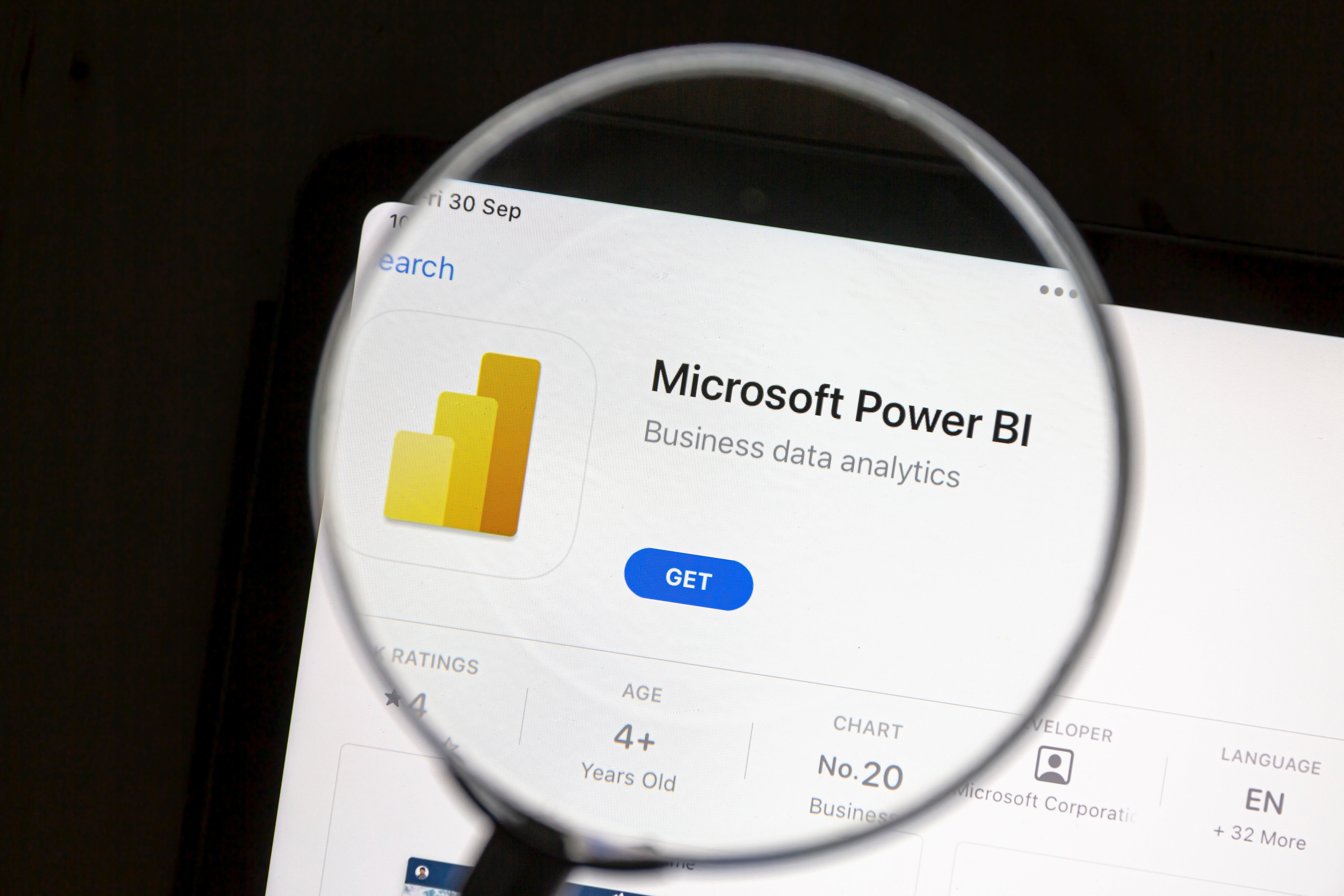 Image of a magnifying glass hovering over the Microsoft Power BI app on a screen.