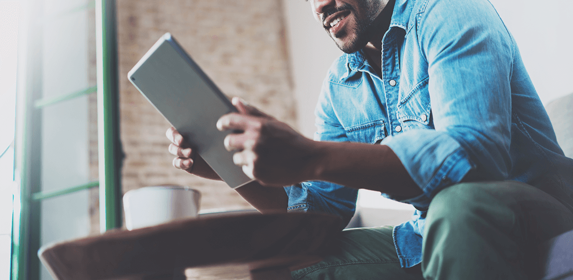 Young male sat at a table looking at his iPad