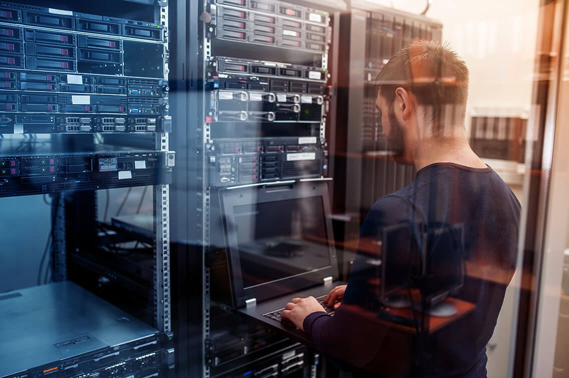 young it engeneer business man with thin modern aluminium laptop in network server room