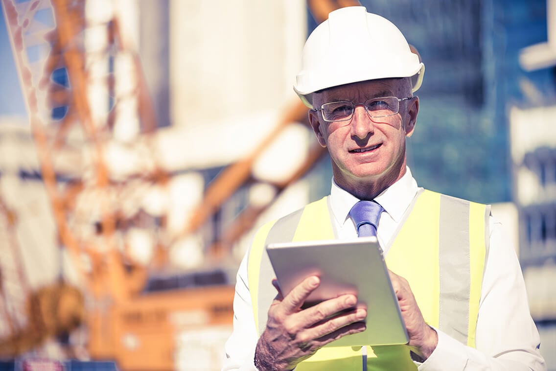 Senior engineer man in suit and helmet working on tablet pc