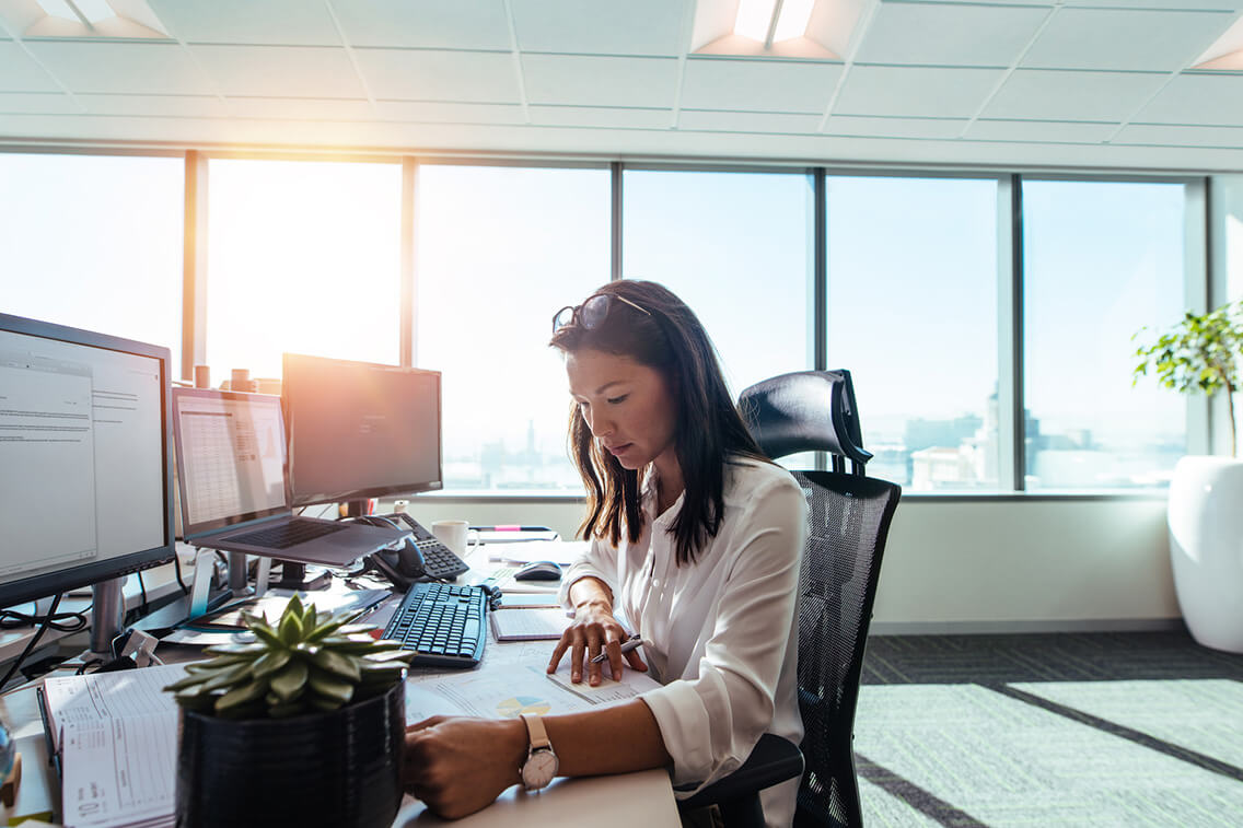 Businesswoman studying business papers on her desk. Woman working in office sitting at her desk.