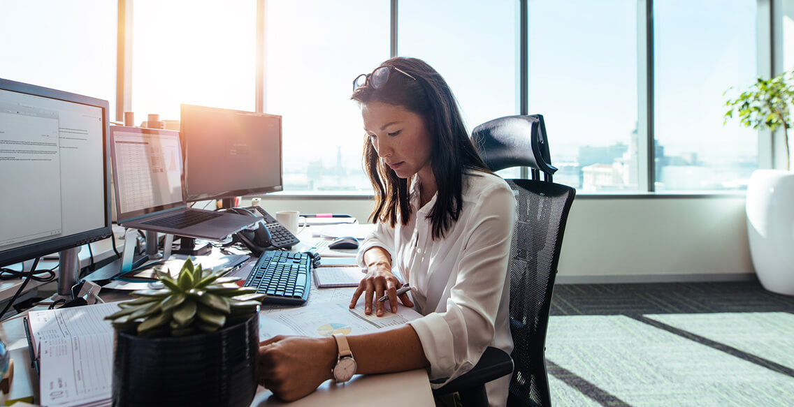 Businesswoman studying business papers on her desk. Woman working in office sitting at her desk.