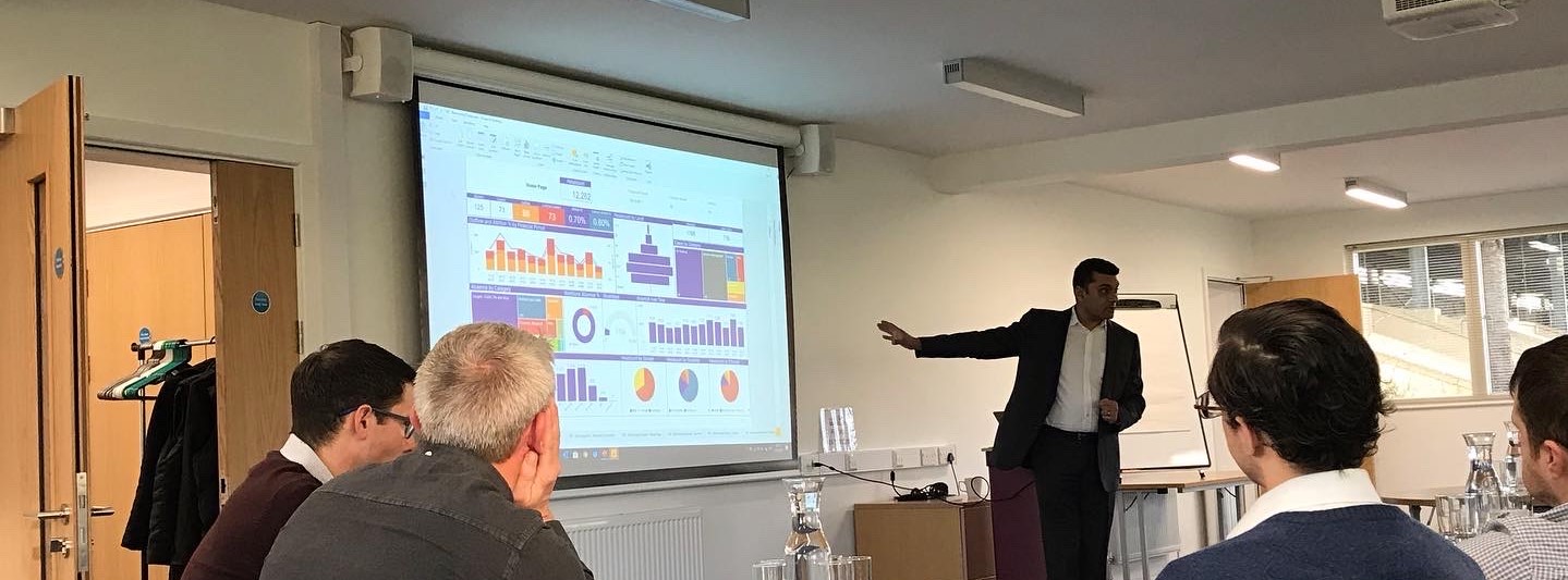 Man presenting a data dashboard in front of a crowded room