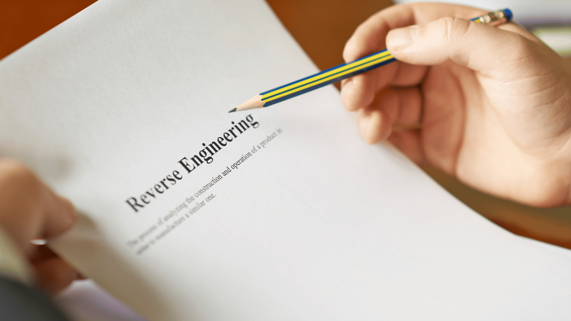 Person with a pencil hovering of the words Reverse Engineering on a piece of paper.