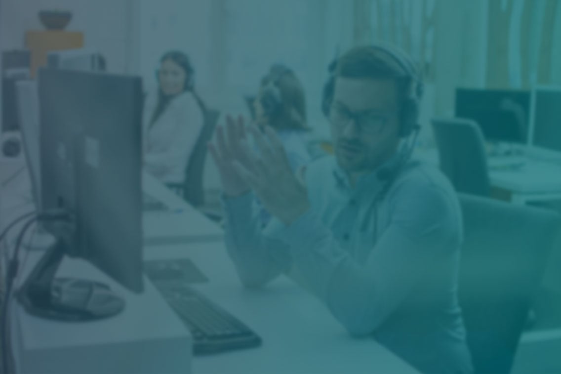 Young male technical support agent trying to explain something to a client while using hands-free headset at call center