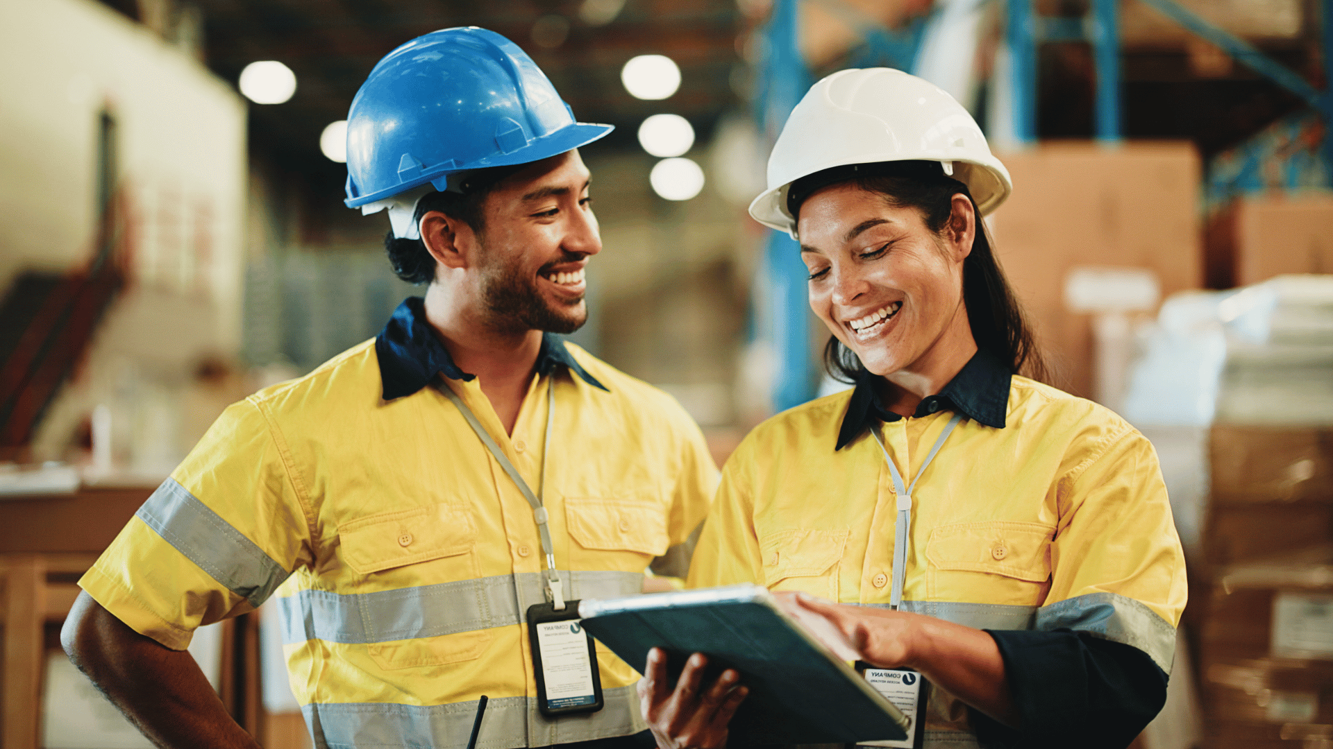 Two workers in protective helmets reviewing documentation inside a warehouse, representing supply chain operations and vendor oversight
