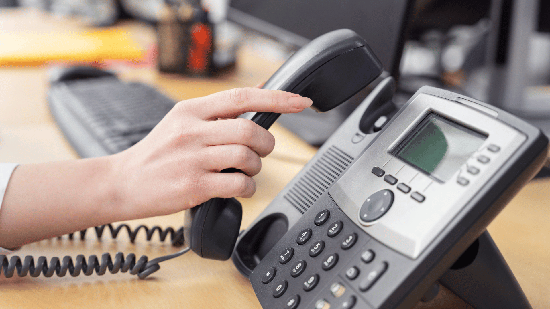 A person picking up a traditional phone line which would run on a Public Switched Telephone Network (PSTN).