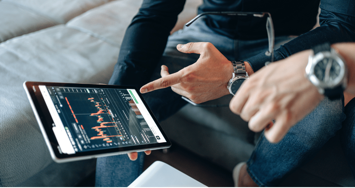A photo of two people sat down pointing towards a tablet showing digital transformation graphs and statistics. 