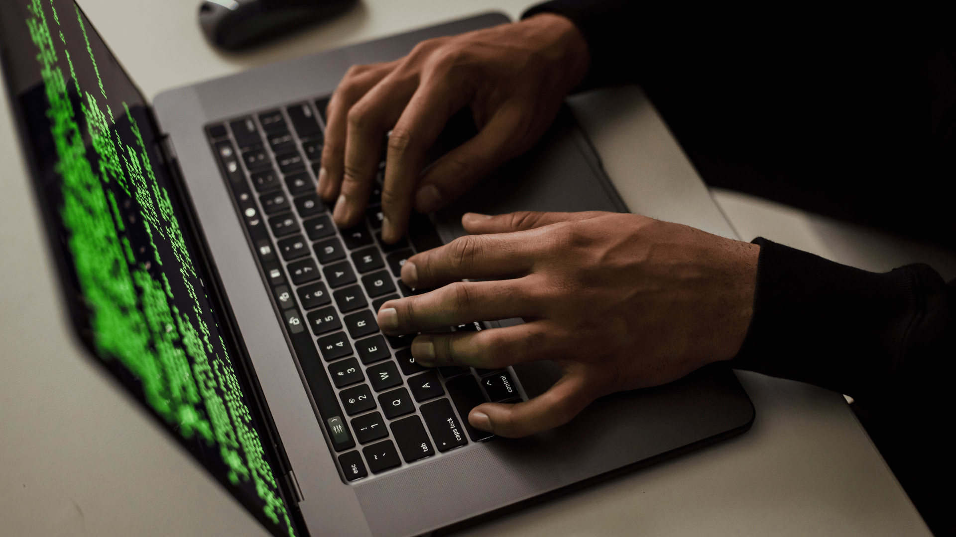 Legal hacker typing green code onto a laptop.