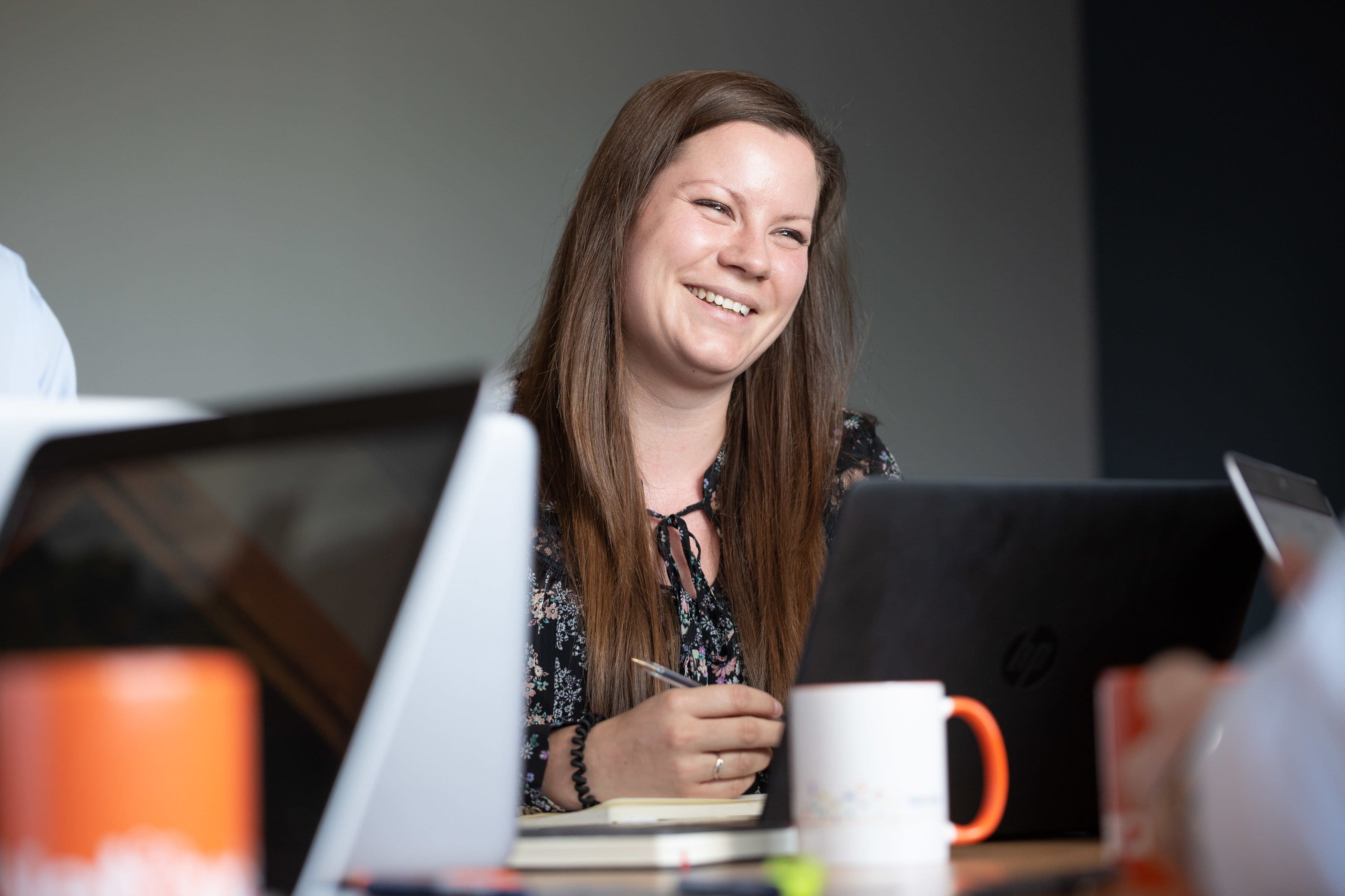 Young female Finance & HR Manager smiling in a meeting with colleagues not pictured