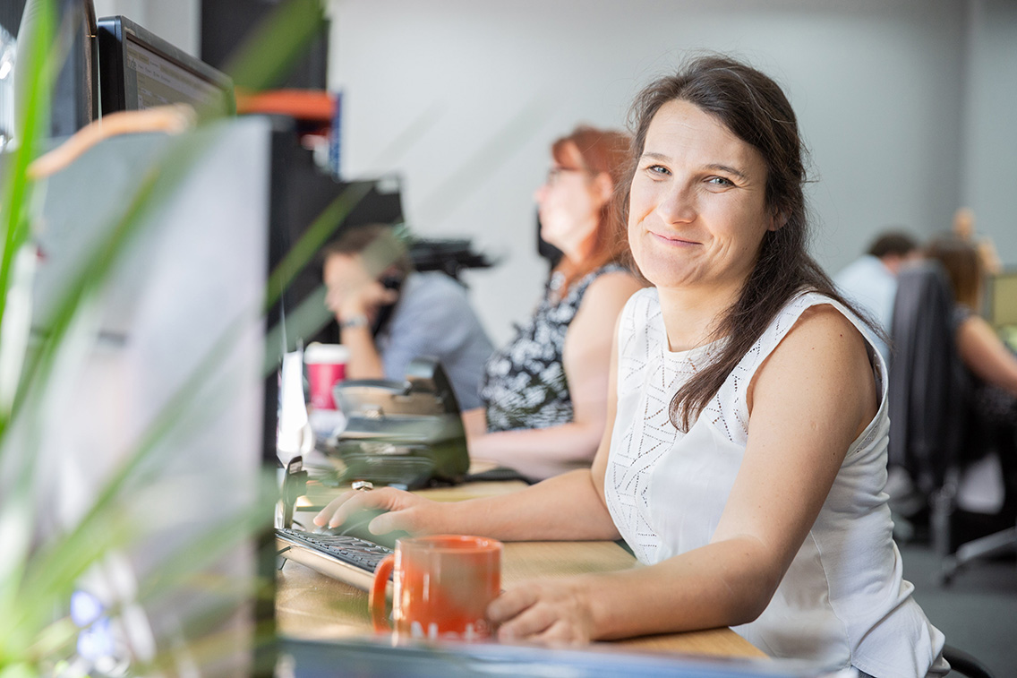 Solutions Coordinator, working at her computer while smiling