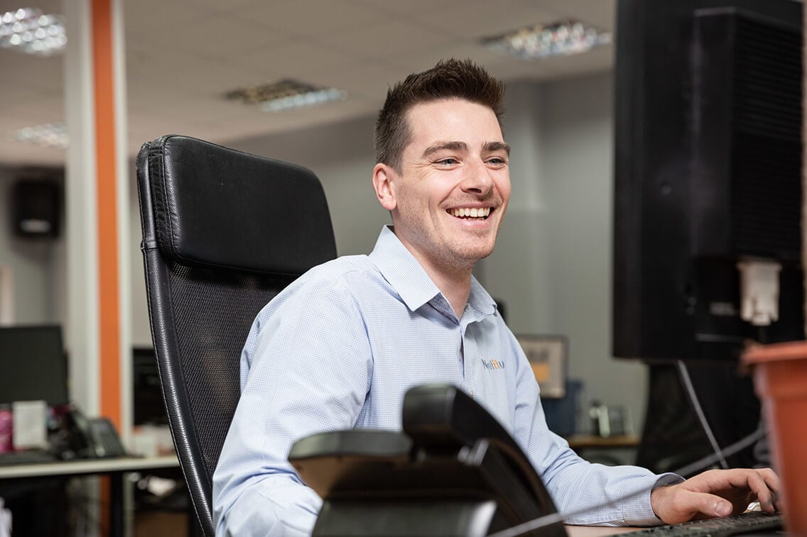 Young male engineer laughing while working at his computer