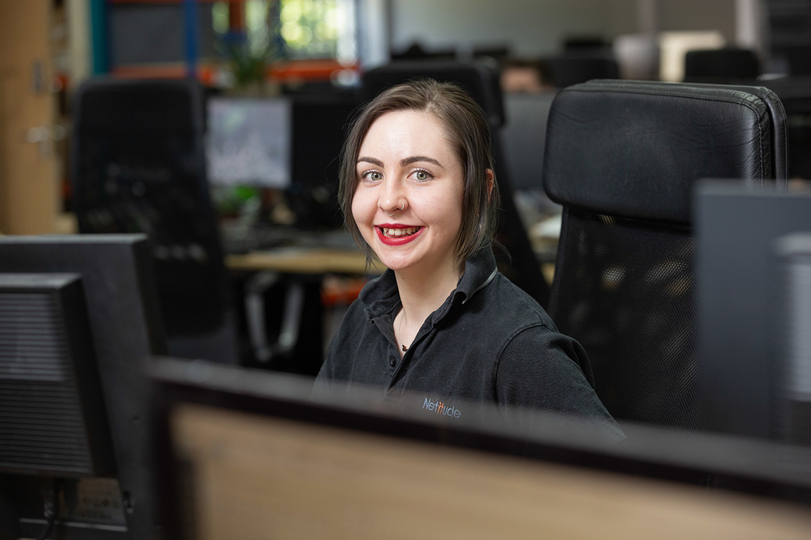 Customer Service Manager smiling at the camera while working at her computer