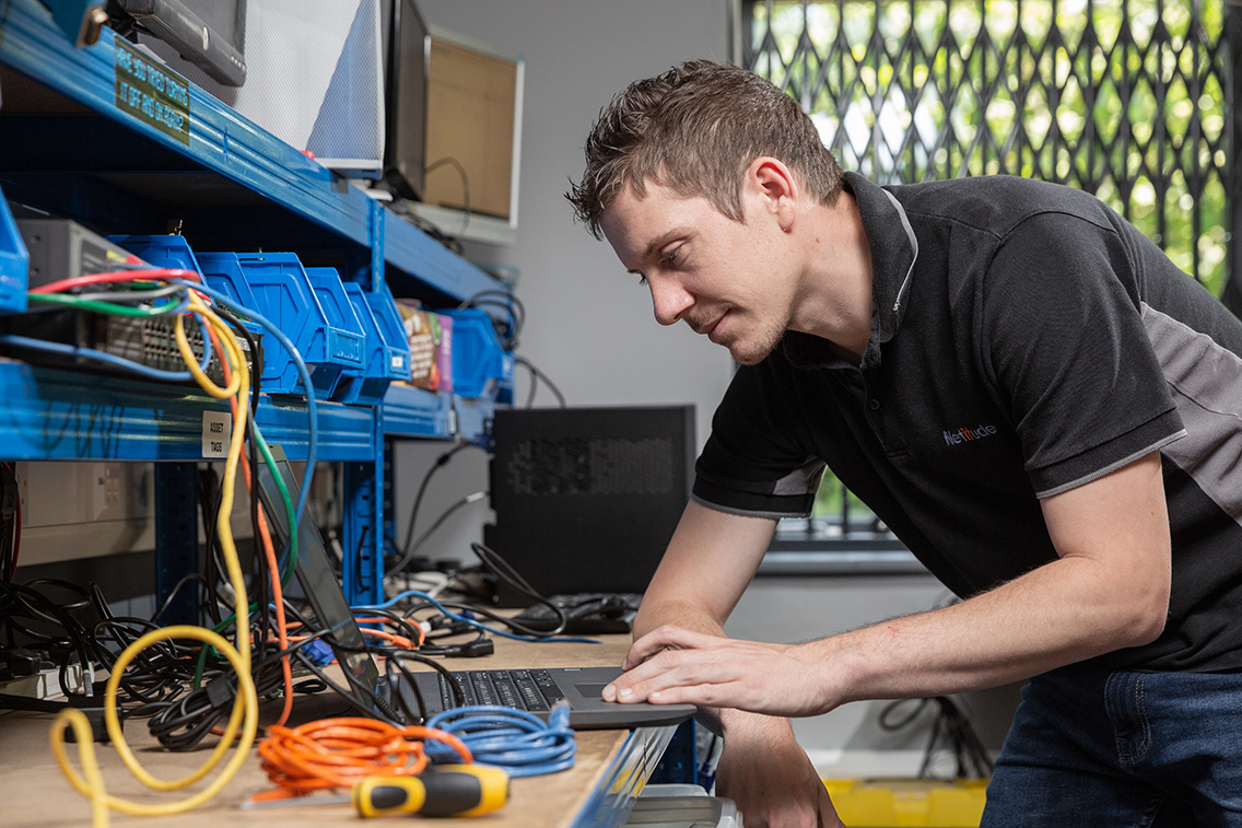 Young male Project Enigneer setting up a new laptop at a build desk