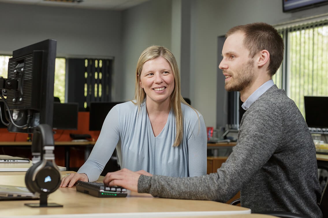 A female manager and male Virtual IT Director having a discussion while working at a computer together